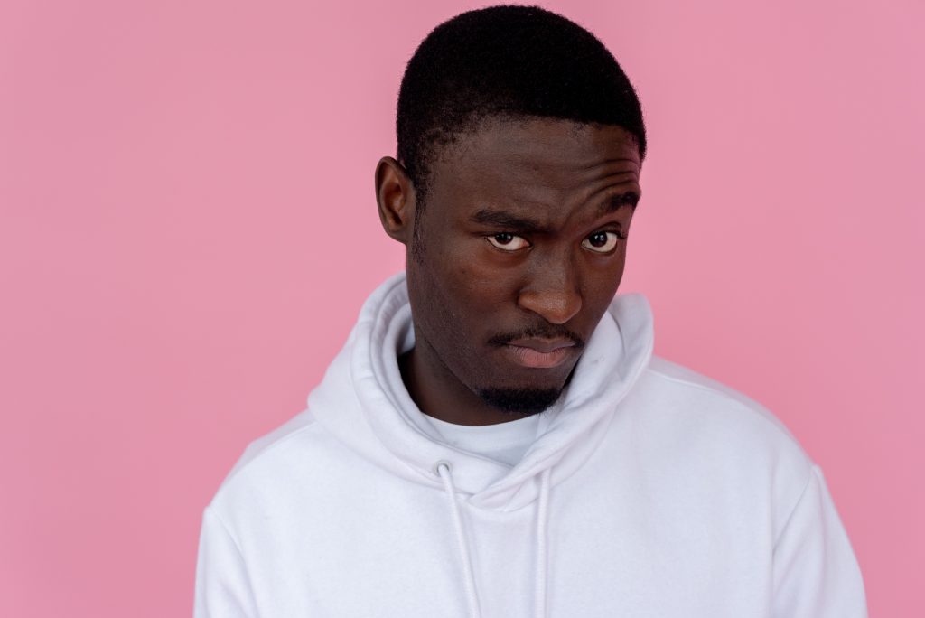 Why Gaming Content Needs More Than Good SEO Serious African American male model wearing white sweatshirt looking at camera with unsure gaze against pink background