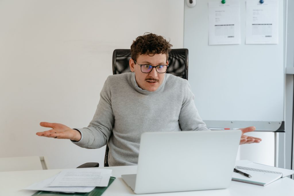 Why Gaming Content Needs More Than Good SEO A man in a gray sweater and glasses gesturing at his laptop screen during a video call in an office setting.